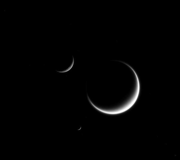 A single crescent moon is a familiar sight in Earth's sky, but with Saturn's many moons, you can see three or even more. The three moons shown here are Titan (3,200 miles or 5,150 kilometers across), Mimas (246 miles or 396 kilometers across), and Rhea (949 miles or 1,527 kilometers across). This view looks toward the anti-Saturn hemisphere of Titan. North on Titan is to the right. Credit: NASA.