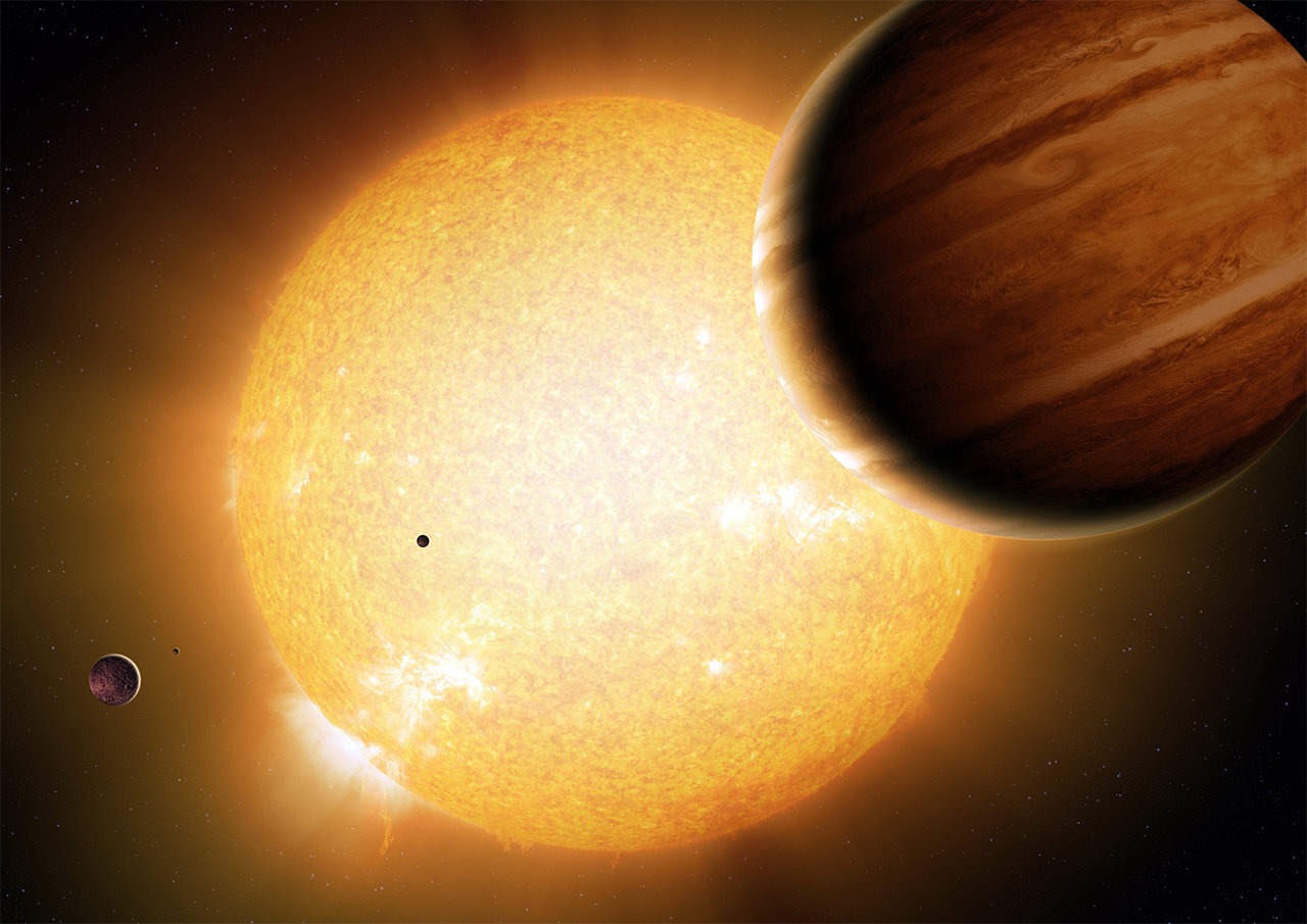 An artist’s portrayal of a warm Jupiter gas-giant planet (right) in orbit around its parent star, along with smaller companion planets. Credit: Detlev Van Ravenswaay/Science Photo Library