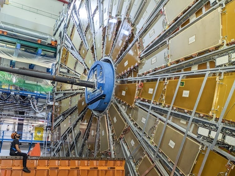 One side of the ATLAS detector at the Large Hadron Collider. The technician on the left faces one of the wheels of the muon chambers — sensors to detect and measure muons. Credit: Ana Peixoto, the ATLAS Experiment at CERN.