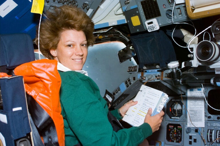 Eileen Collins, mission commander, looks over a checklist on the Space Shuttle Columbia in 1999. Credit: NASA.