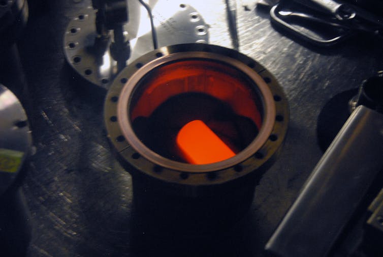 A circular metal container with a glowing cylinder inside.