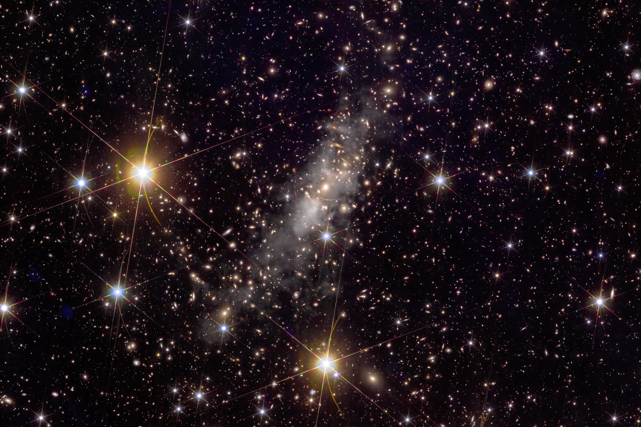 Arcs of light from background galaxies appear among the galaxies of Abell 2390. The gray “haze” is intracluster light emitted by stars that were expelled from their home galaxies. Such stellar orphans may help astronomers to “see” where dark matter is located. Credit: ESA/Euclid/Euclid Consortium/NASA, image processing by J.-C. Cuillandre (CEA Paris-Saclay), G. Anselmi